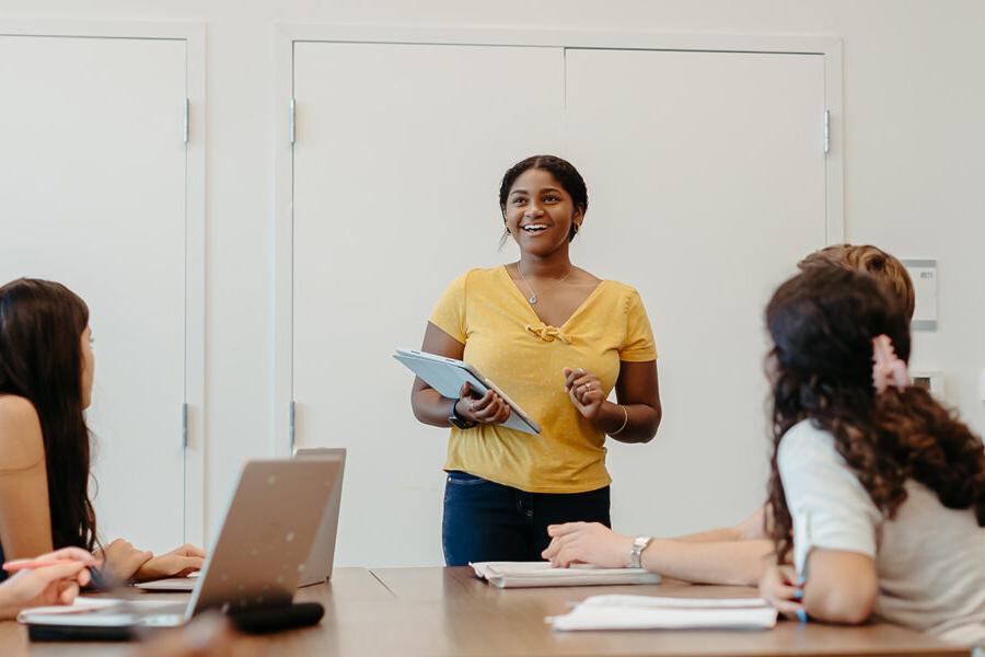 a smiling student presents in class to other students